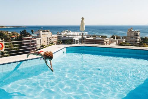 雅典艾曼狄纳酒店的跳进建筑物顶端的游泳池的人
