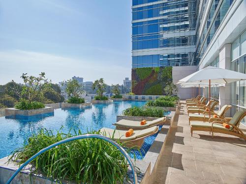班加罗尔班加罗尔香格里拉酒店的酒店设有带椅子和遮阳伞的游泳池