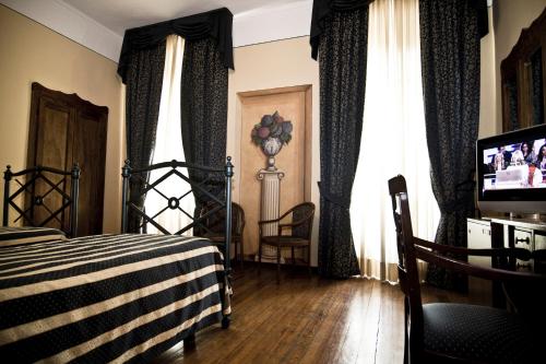 皮内罗洛雷吉纳酒店的一间卧室配有床、电视和窗帘