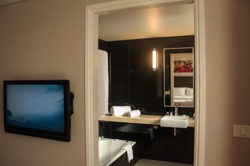 蒙得维的亚AXSUR迪赛恩酒店的一间带镜子和水槽的浴室以及一台电视