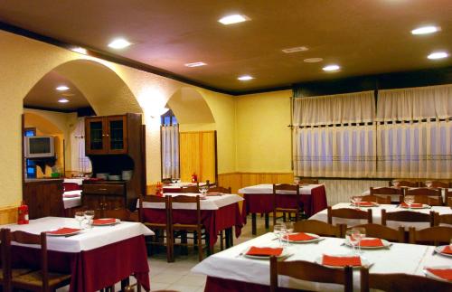 索特Hostal Les Collades的餐厅设有桌椅,配有红色和白色的桌布