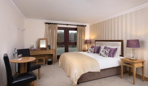 里南德尔福度假村及Spa的一间卧室配有一张床、一张桌子和一把椅子