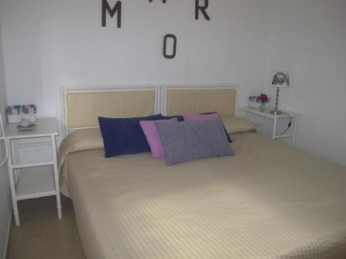 卡门港奥瑞玛公寓的一间卧室配有一张带紫色和蓝色枕头的床