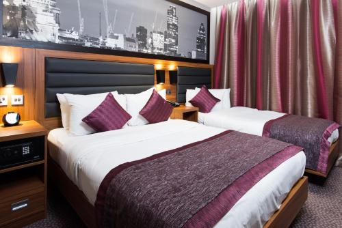 伦敦London Court Hotel的酒店客房设有两张床和一张带照片的墙壁