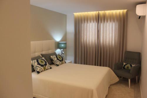卡武埃鲁Apartamento Morning Cascade的卧室配有一张白色大床和一把椅子