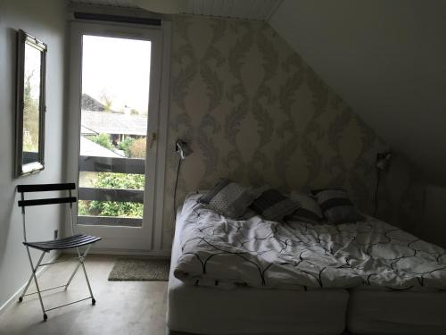 Hareskovby巴格斯瓦尔德公寓的一间卧室设有一张床、一个窗口和一把椅子
