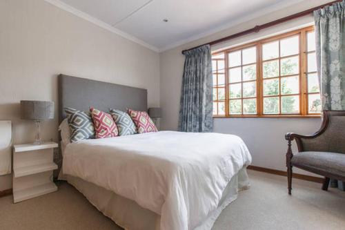 约翰内斯堡Sandown Estate Apartment的卧室配有床、椅子和窗户。