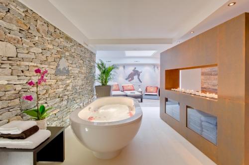 采尔马特Alex Lodge Private Luxury Apartments的带浴缸和石墙的浴室