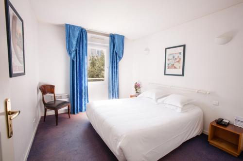 比亚里茨比亚里茨海洋酒店的卧室配有白色的床和蓝色窗帘