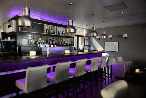 德科赫库艮弗莱彻餐厅酒店 的餐厅内拥有紫色照明的酒吧