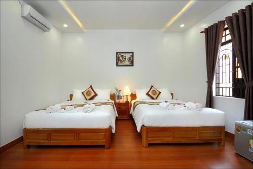 会安蓝湖民宿的一间卧室设有两张带白色床单的床和窗户。