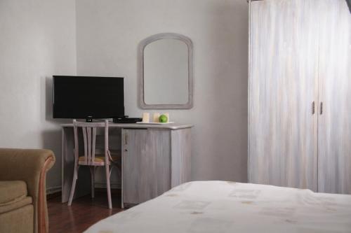 尤尔马拉坦尼撒克鲁斯尤拉酒店的一间卧室配有一张桌子、一台电视和一面镜子