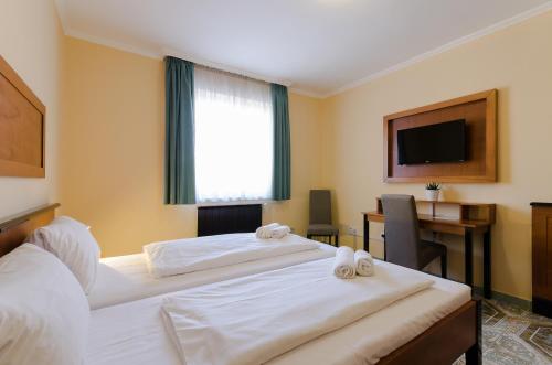 布达佩斯Richter Pansion的酒店客房设有两张床、一张桌子和一台电视。