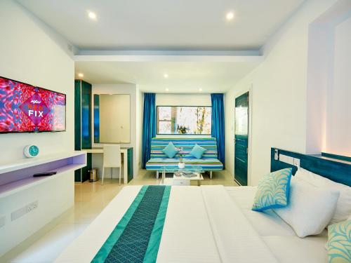 胡鲁马累浮游生物海滩酒店的卧室配有一张白色大床和电视。
