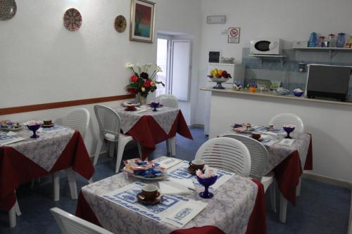 伊斯基亚阿丽博格鲁康达苏鲁玛尔酒店的用餐室配有2张桌子和白色椅子