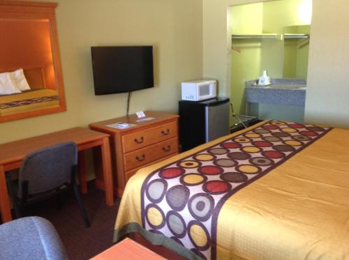 Pryor普赖尔美国最有价值旅馆的酒店客房配有一张床、一张书桌和一台电视。