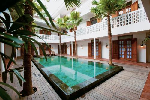 日惹日惹加持酒店的一座种植了棕榈树的室内游泳池