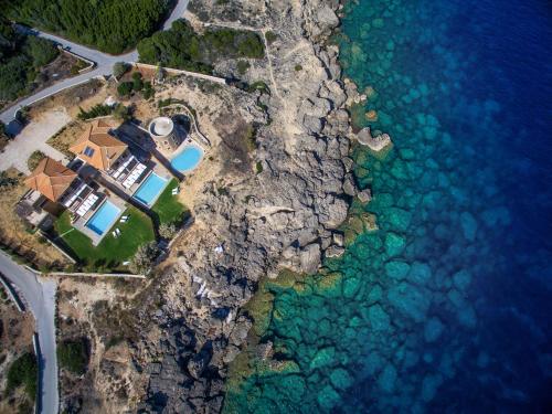 瓦西里科斯Armonia Seaside Villas的靠近水面的悬崖上房屋的空中景观