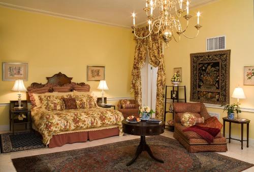 拿骚灰崖酒店的一间卧室配有一张床、一把椅子和一个吊灯。