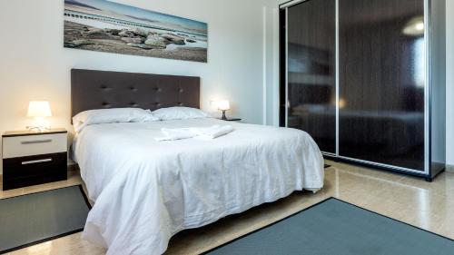 塔拉哈勒赫Tarajalejo Village的卧室配有一张白色大床和玻璃淋浴间