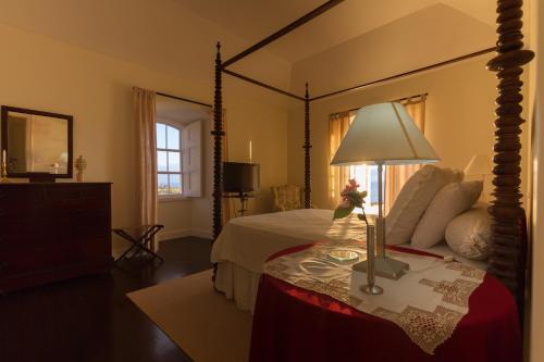 拉戈阿Casa da Rocha Quebrada的一间卧室配有一张大天蓬床和一张带台灯的桌子