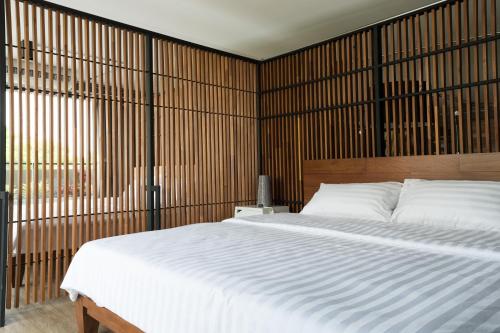 清迈诺德公寓的卧室配有一张白色大床和木墙