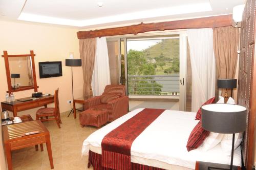 KyabinungaIgongo Country Hotel & Cultural Centre的配有一张床、一张书桌和一扇窗户的酒店客房