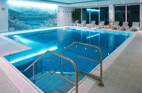 加尔米施-帕滕基兴加米施帕滕基兴美居酒店的大楼内带椅子的大型游泳池