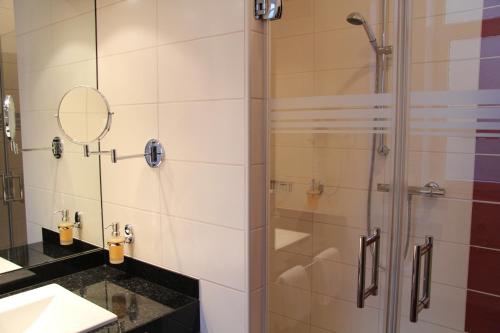 不来梅港阿迪那酒店的带淋浴的浴室和玻璃门