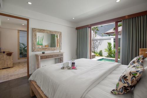 沙努尔两蜥蜴海滩别墅的一间卧室配有一张大床和镜子