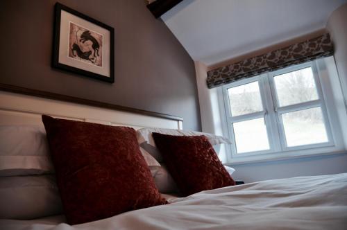 巴恩斯特珀尔Pyne Arms的一间卧室配有带两个枕头的床和窗户