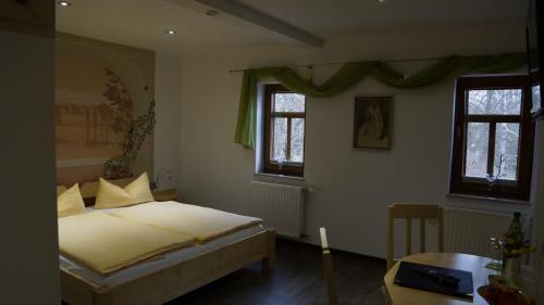 Herbsleben穆乐哈特旅馆的一间卧室配有一张床、一张桌子和两个窗户