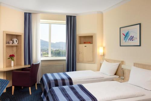 弗莱堡佛赖堡城际酒店的酒店客房设有两张床、一张书桌和一个窗户。