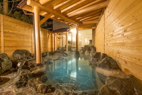白马村白马摩米农垦酒店 的一座木房子里一座带岩石的游泳池