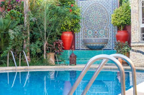 埃尔哈豪拉阿罕布拉传统庭院酒店的一个带红色花瓶和瓷砖墙的游泳池