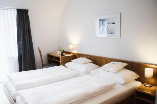 雄高Hotel Blaue Traube的配有白色床单的酒店客房内的两张床