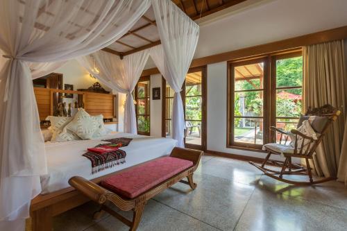 佩母德兰塔曼沙丽巴厘Spa度假酒店的卧室配有一张白色大床和一把椅子