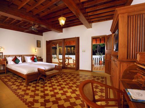 Kānādukāttān池达巴瑞维拉斯度假村 - 豪华遗产度假胜地的卧室配有一张床和一张桌子及椅子