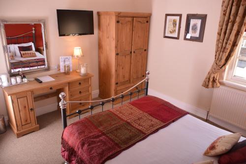 约克约克玫瑰与皇冠宾馆的一间卧室配有一张床、一张书桌和一面镜子