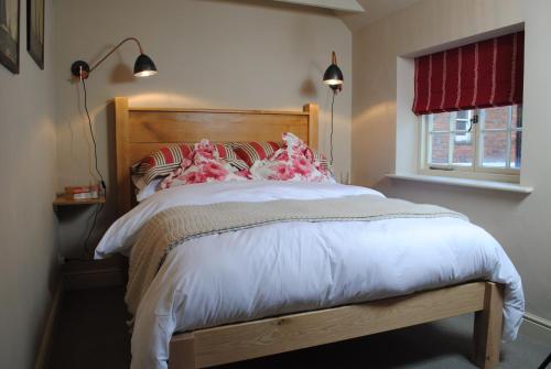 利明顿Courtyard Cottages Lymington, 2 Adults only的一间卧室配有一张带木制床头板的床和窗户。