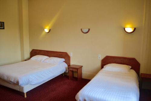 埃夫勒格兰德酒店的一间设有两张床的房间和墙上的两盏灯