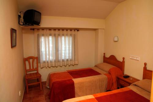 Yunquera de HenaresHostal La Granja的酒店客房设有两张床和电视。