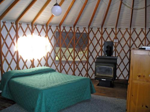 Harden Flat约塞米蒂湖山尤特14号假日公园的蒙古包内一间卧室配有一张床和一个炉灶