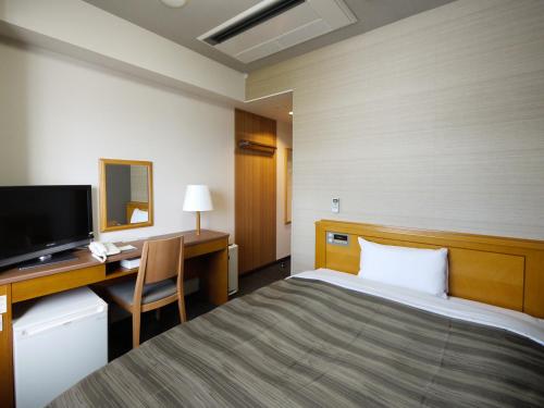 秋田秋田市土崎路线酒店的酒店客房配有一张床、一张书桌和一台电视。