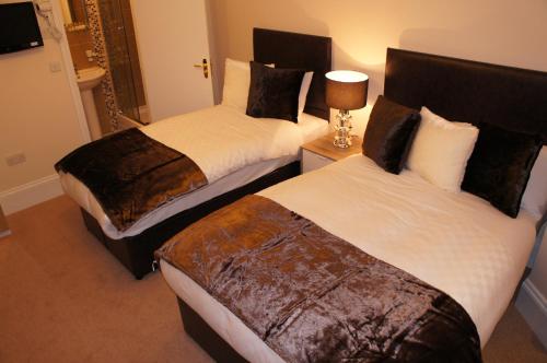 伦敦伦敦蓝宝石酒店的配有衬衫的酒店客房内的两张床