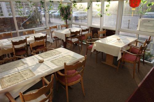 巴特布拉姆施泰特快乐之家酒店的餐厅设有白色的桌椅和窗户。