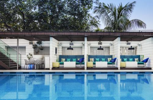 加尔各答加尔各答公园酒店的一座游泳池,旁边设有蓝色和黄色的家具