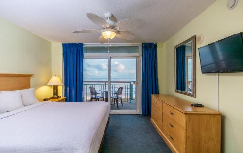 默特尔比奇天堂度假酒店的一间卧室配有一张床、一台电视和一个阳台