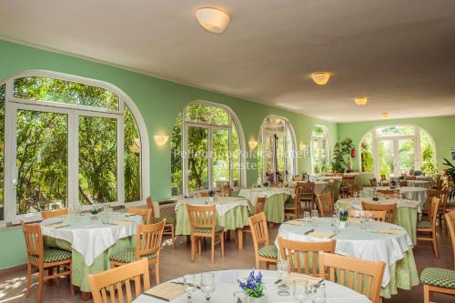 维耶斯泰佩莱格里诺宫俱乐部酒店的餐厅设有白色的桌椅和窗户。