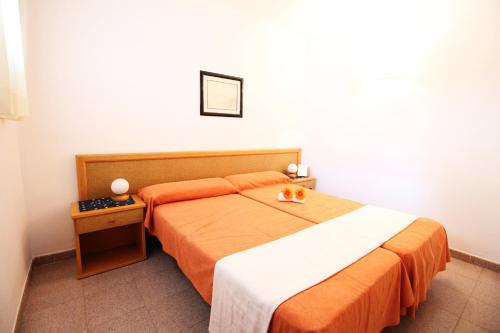 萨洛Mariposa 1023 IBERPLAYA的一间卧室配有一张带橙色和白色毯子的床